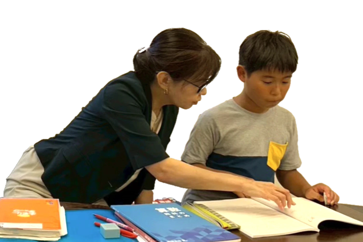 教室でお子さまの教材を確認しながら指導するなみ先生